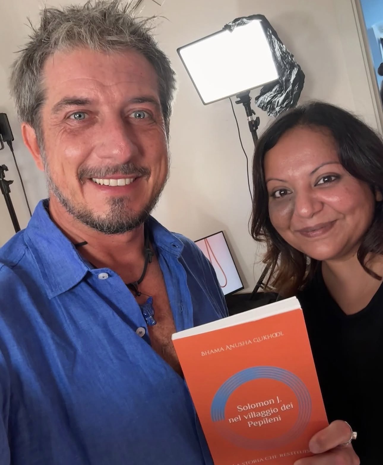 Anusha Bhama Gukhool con Paolo Ruffini sul set del programma Mamme, mentre tiene in mano il libro Solomon J. nel villaggio dei Pepileni